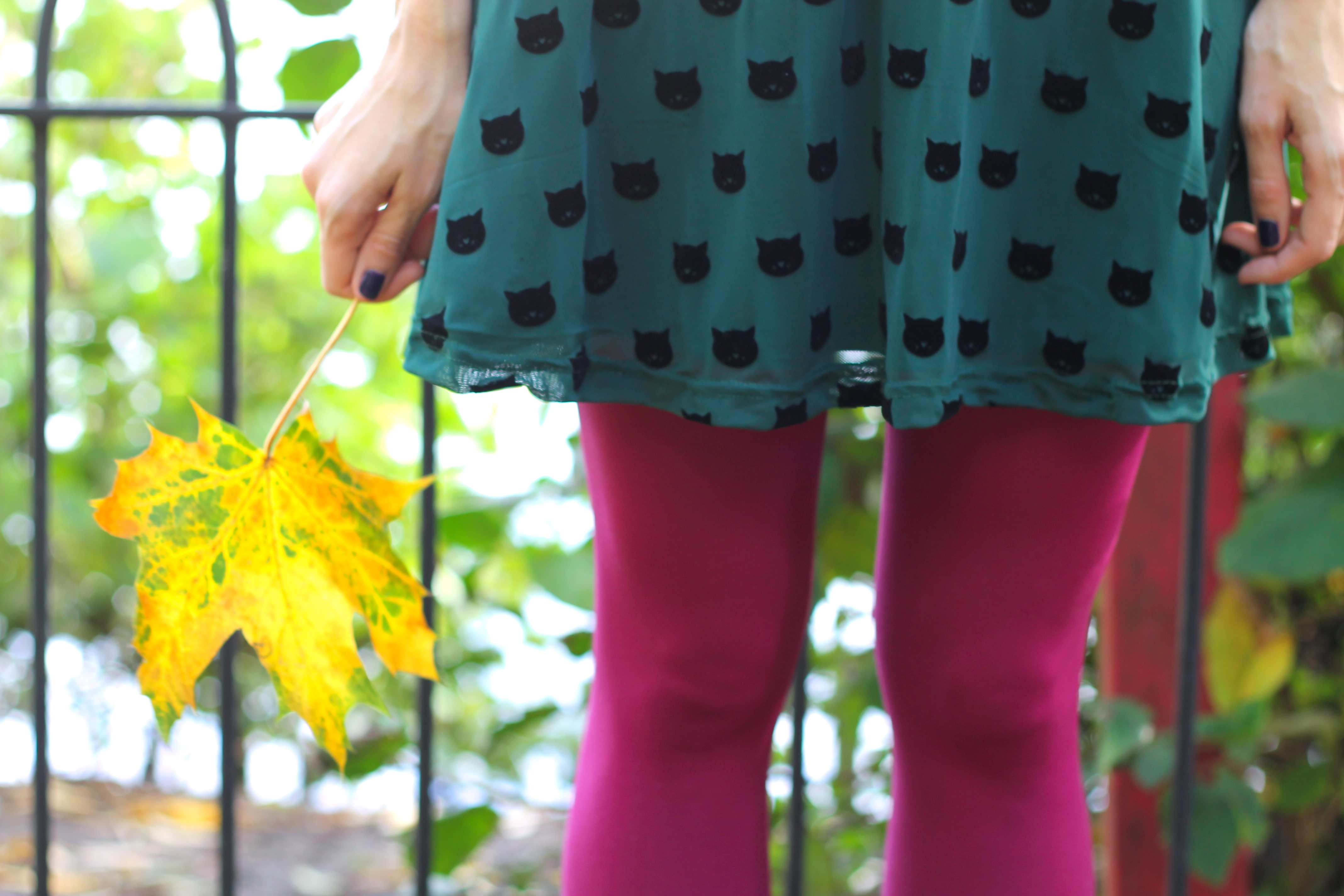 girl in pink tights and a green dress holding a yellow leaf